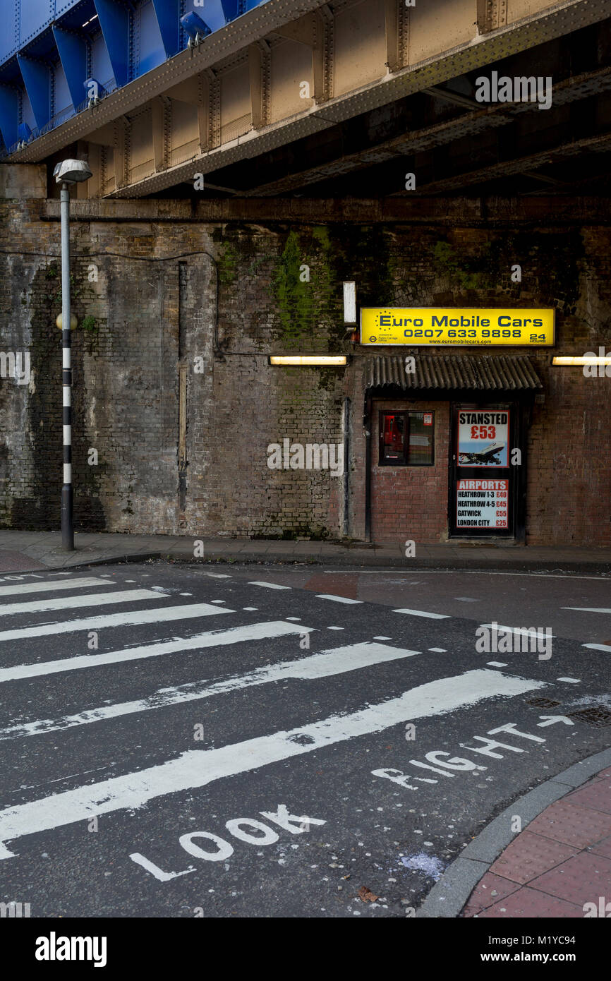 A taxi cab office advertising airport run fairs beneath a Victorian