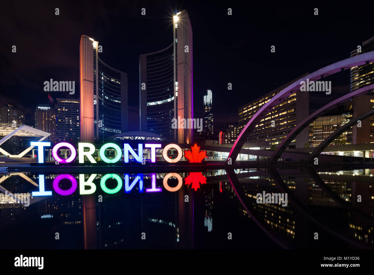 The Toronto PanAm sign lit up and Toronto City Hall reflected in water at the Nathan Phillips Square at night, Toronto, Ontario, Canada Stock Photo