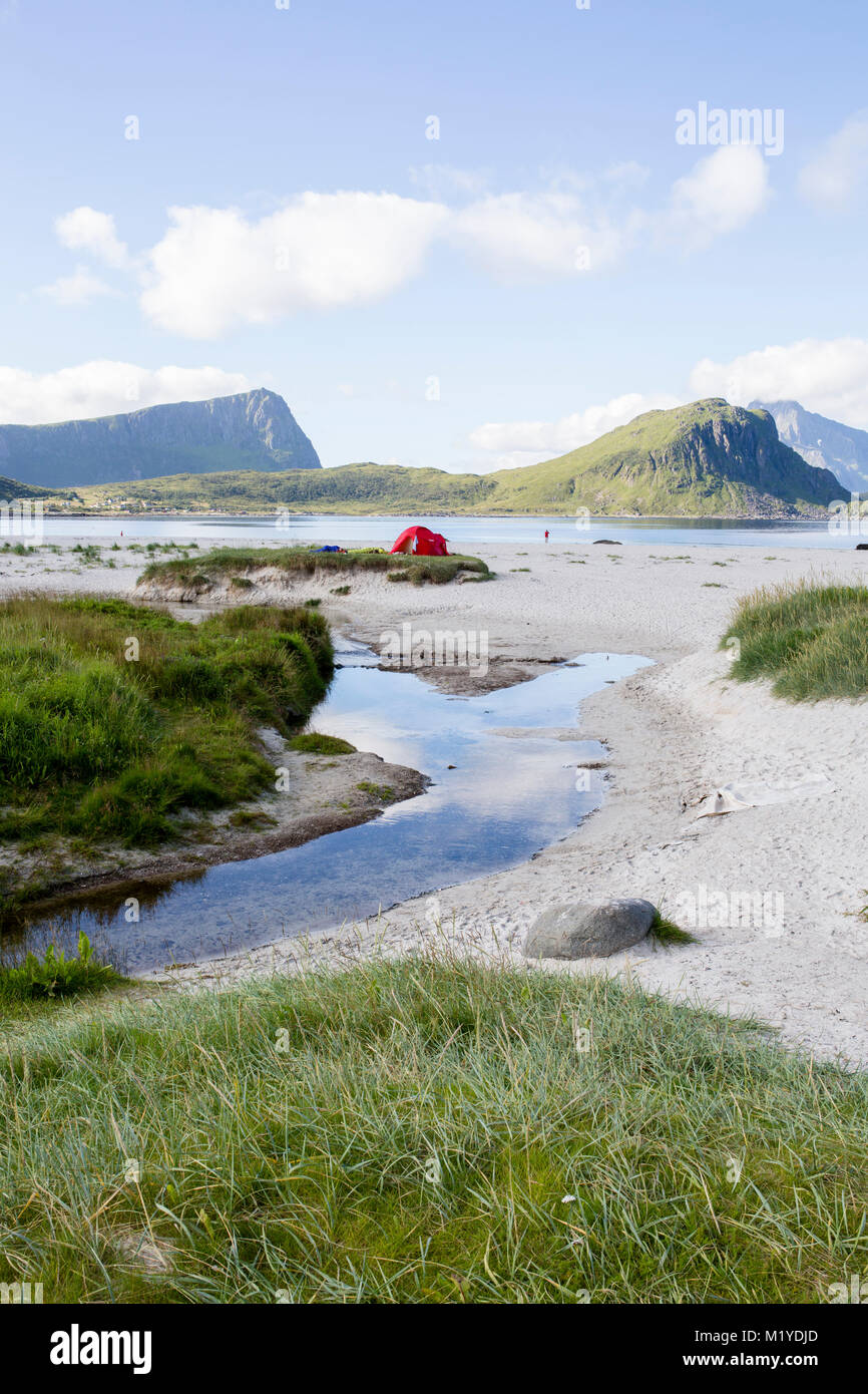 Red tent on green grass near the sand at Haukland Beach, Lofoten Islands, Norway. Stock Photo