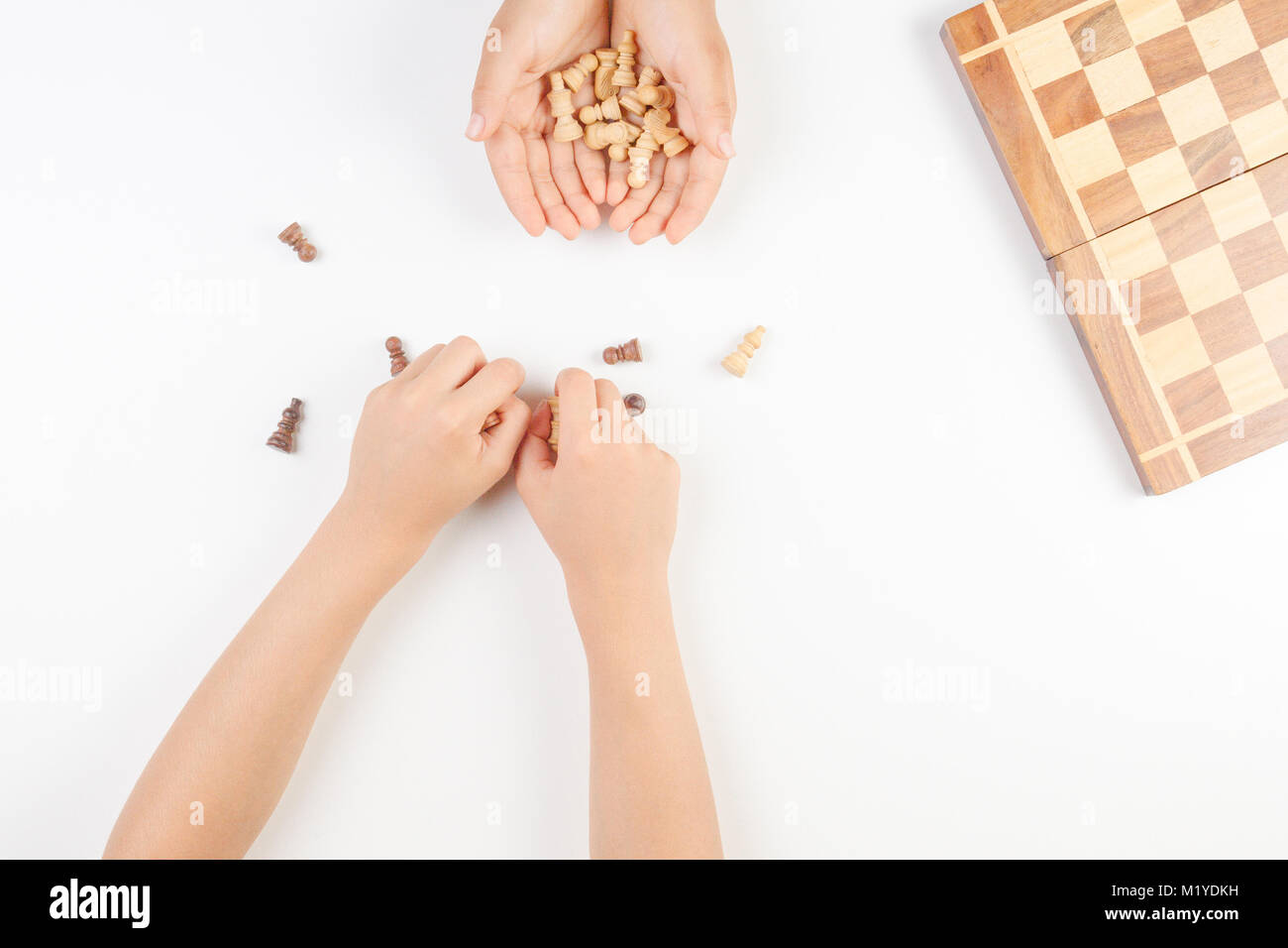Chess board with chess pieces and a playing kids hand. Stock Photo