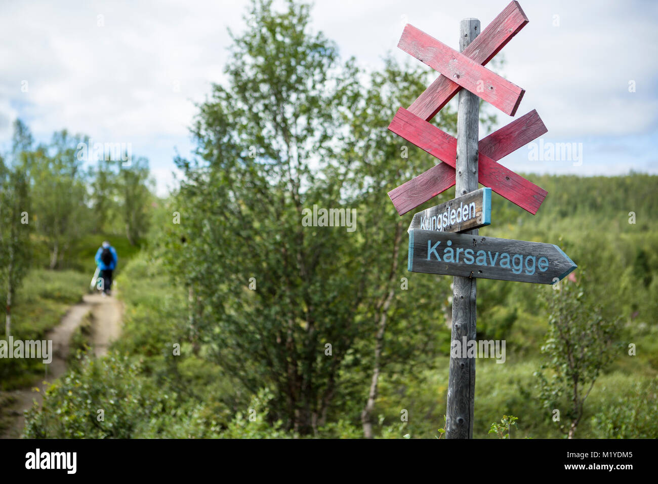 A classic signplate at the walking trail Kungsleden, Lapland, Sweden. Sign is infront and some hikers are seen in background. Stock Photo