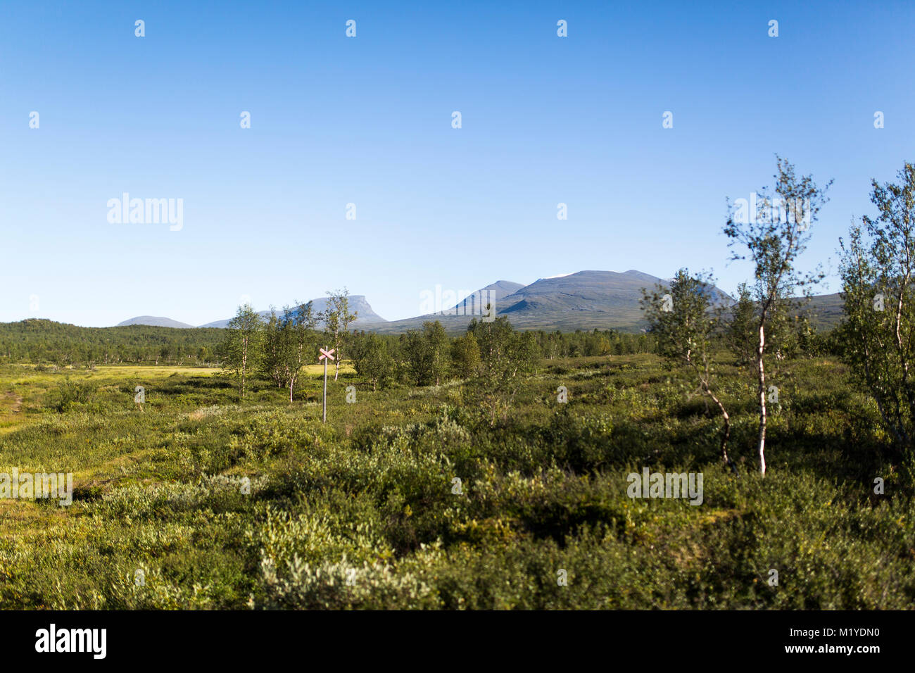 Lapporten, a mountain pass in Lapland, Sweden viewed from far away. A red cross marks out the walking trail in the wild nature. Stock Photo
