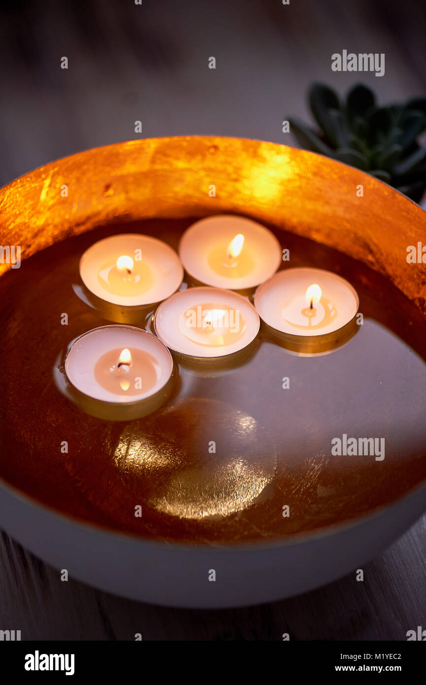 Golden bowl with water in which floating candles.Interior decoration
