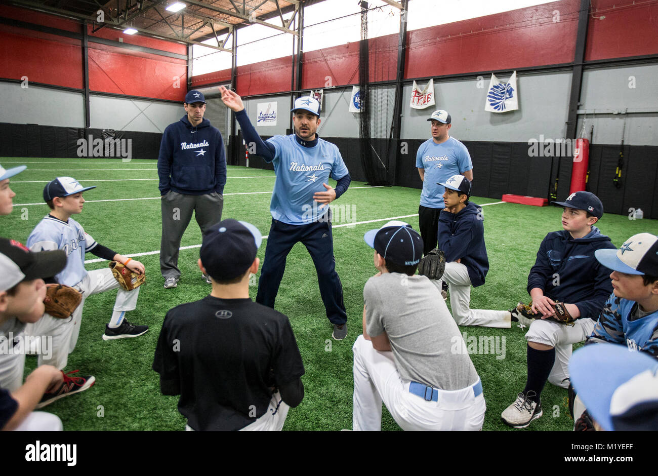 Baseball coach demonstrating proper throwing  technique at an indoor training facility in New Jersey Stock Photo