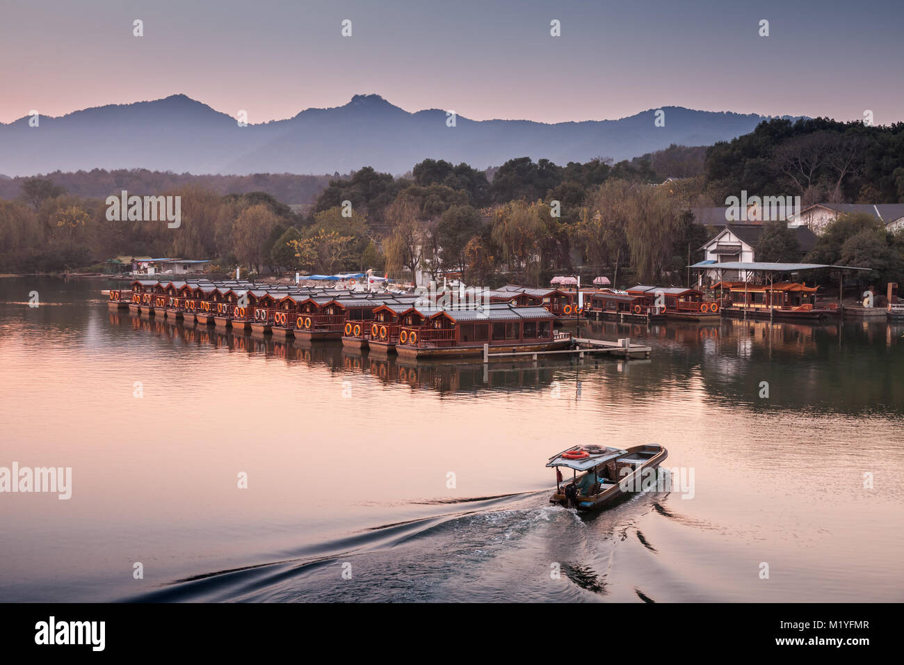 Chinese evening landscape with fishing boat on the West Lake. Famous public park in Hangzhou city, China Stock Photo