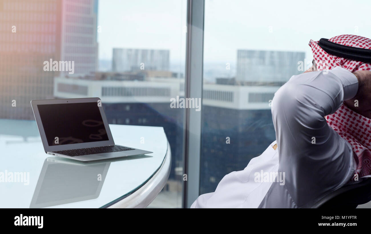 Saudi Arab Man Watching Laptop at Work and Contemplating Stock Photo
