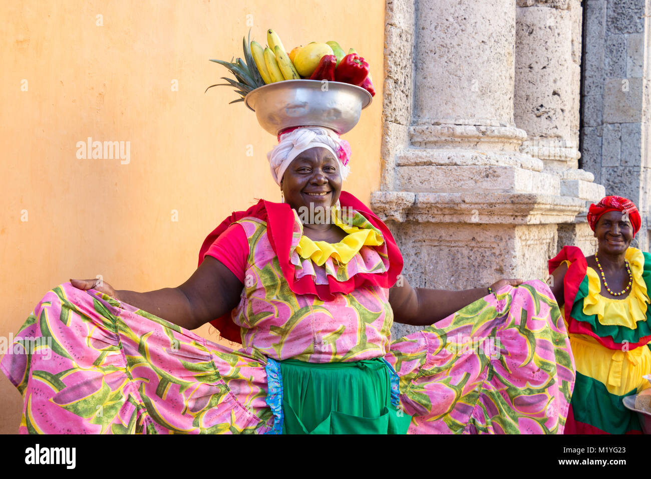 Cartagena, Colombia - January 23th, 2018: A woman palenquera with a metal basket with fruits posing showing her multicolor traditional dress at the ol Stock Photo