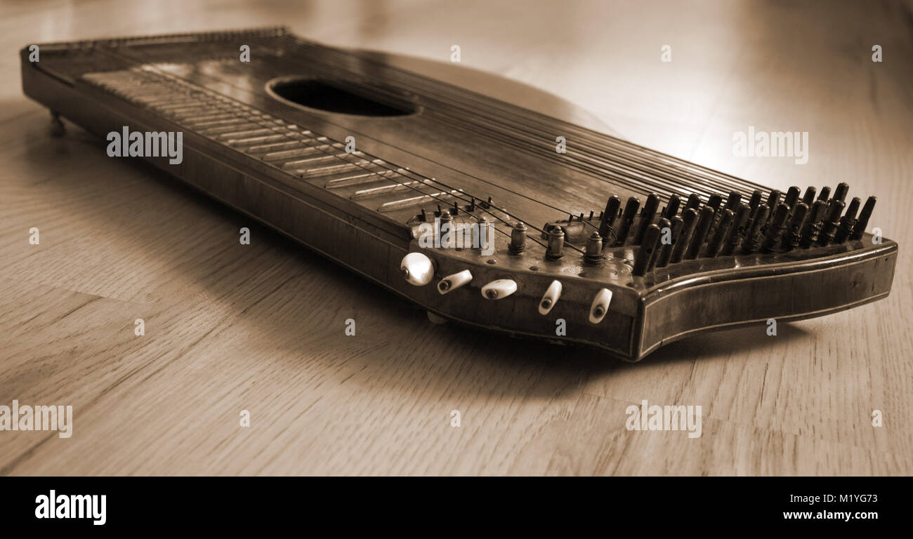 Old zither lying on a wooden table in braun color. Stock Photo