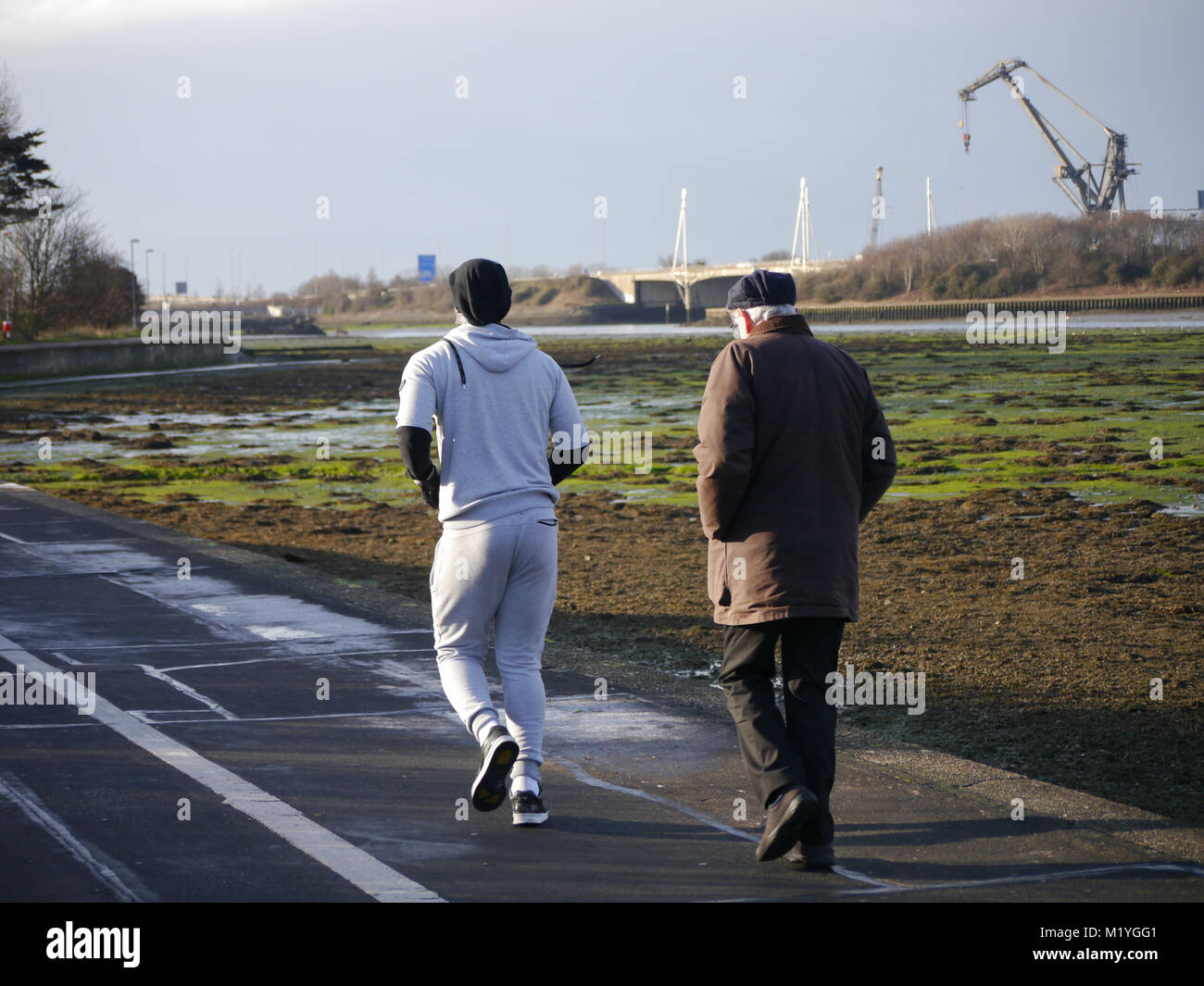 A young man overtakes a senior male whilst jogging Stock Photo