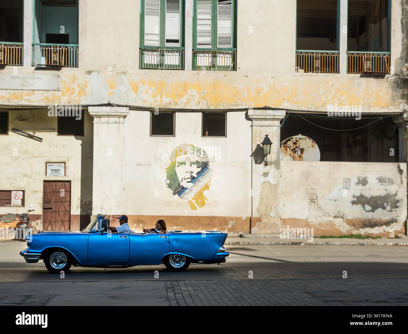 Havana, Cuba - December 3, 2017: blue, old and classical car in road of old Havana (Cuba) and in the background the icon of Che Guevara Stock Photo