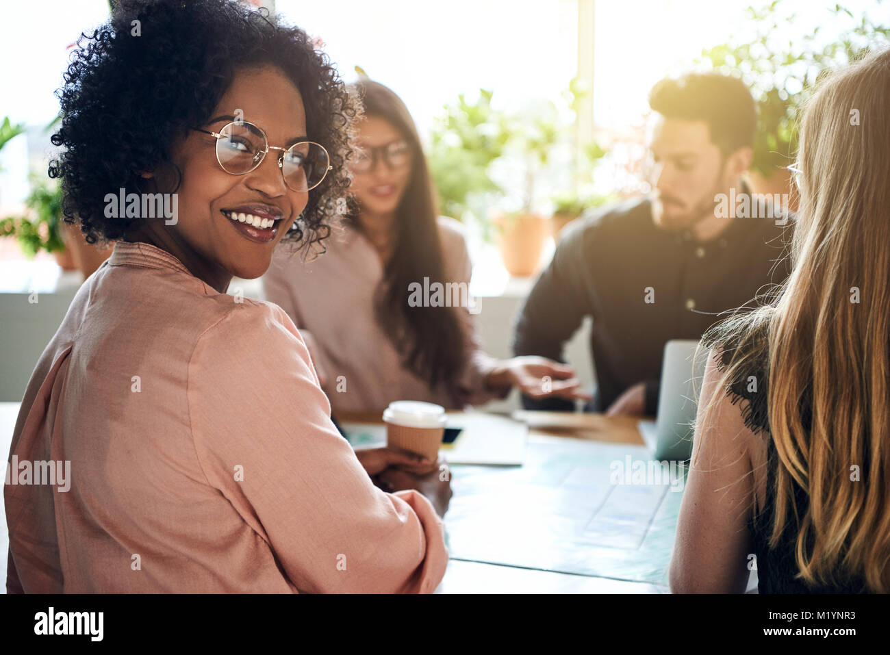 Smiling African businesswoman sitting at an office table looking over ...