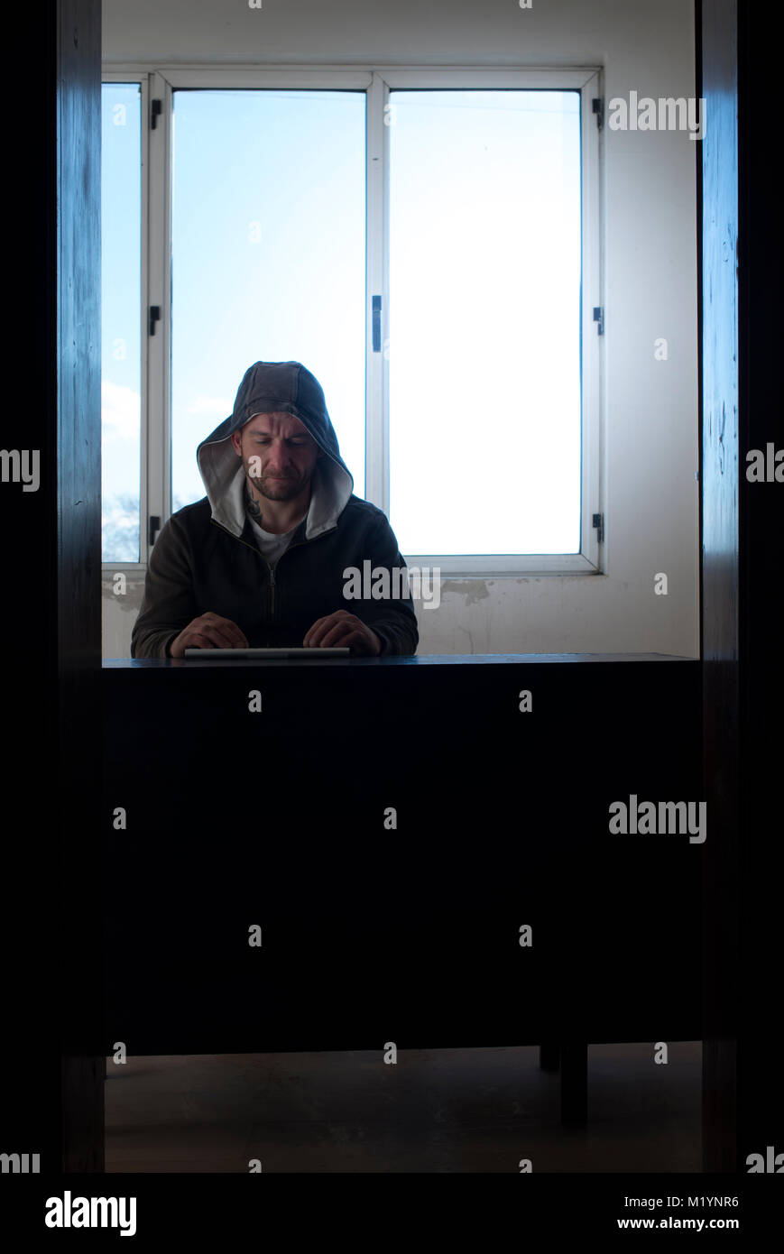 Hacker in a room with illuminated window. Stock Photo