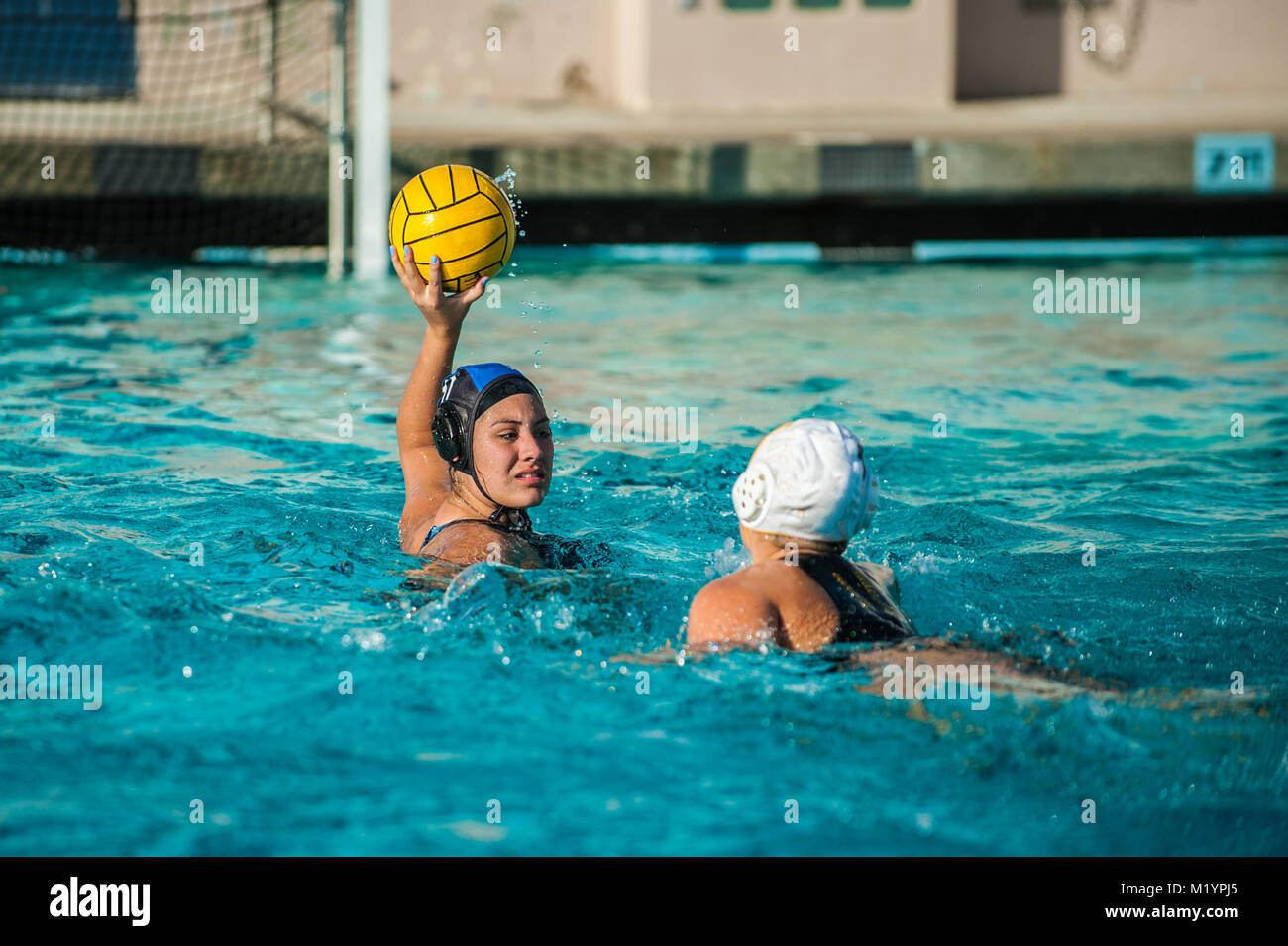 Female water polo athlete holding ball above water and away from