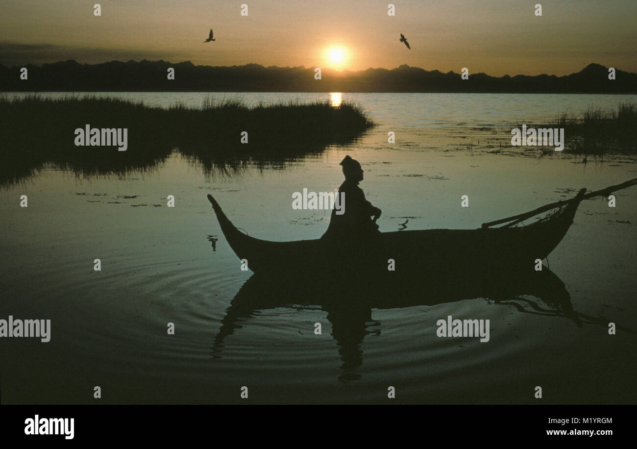 Bolivia. Copacabana. Titicaca lake. Andes mountains. Aymara indian fisherman in reed boat. Sunrise. Stock Photo