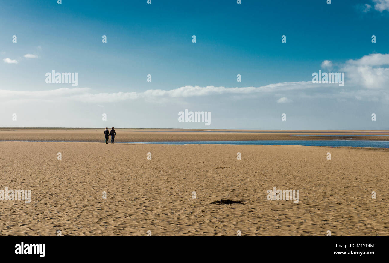 Couple walking on sandy beach Stock Photo - Alamy