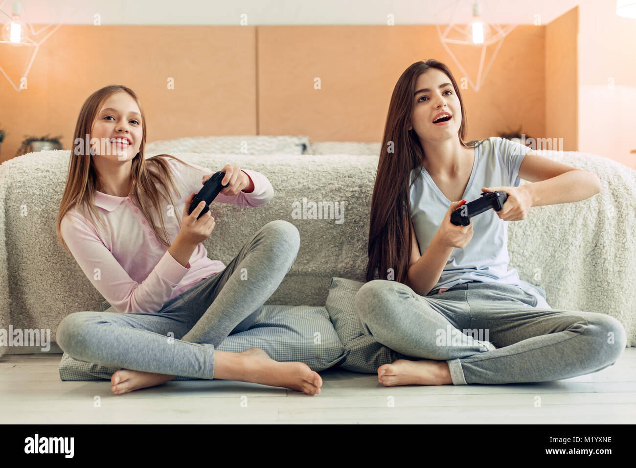 Two teenage sisters playing video game in bedroom Stock Photo