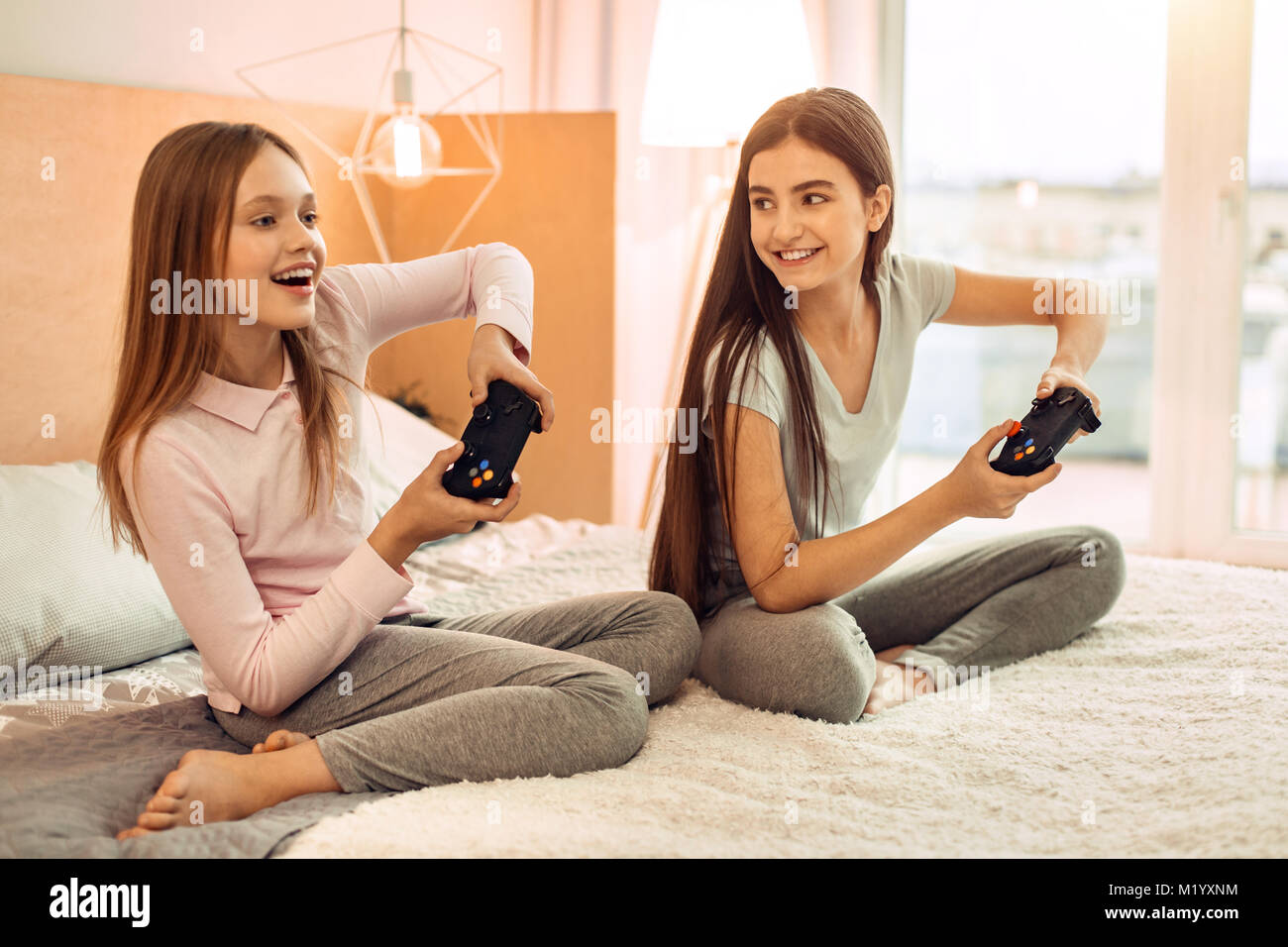 Two teenage sisters playing video game enthusiastically Stock Photo