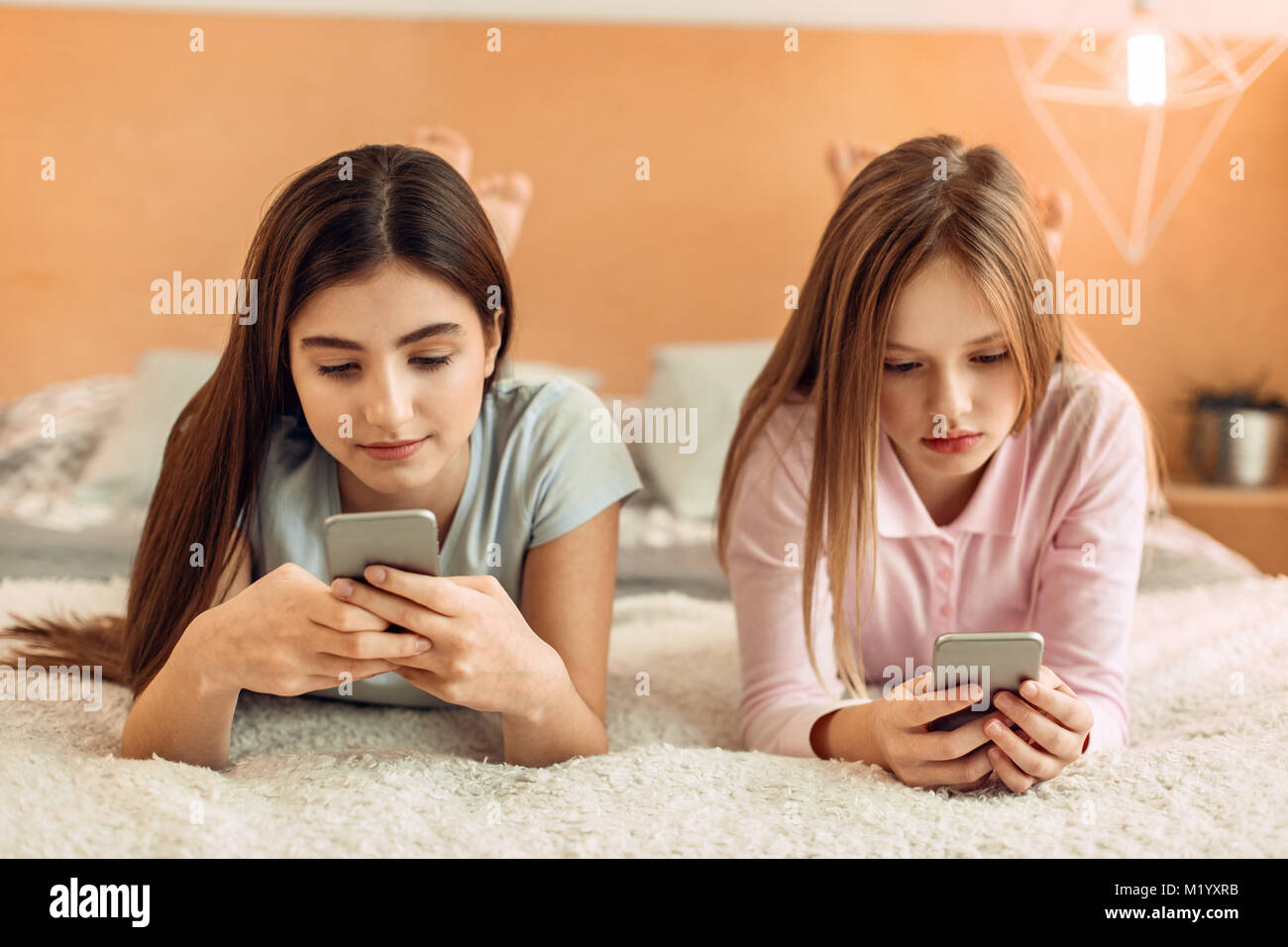 Teenage girls lying on bed and using their phones Stock Photo Alamy
