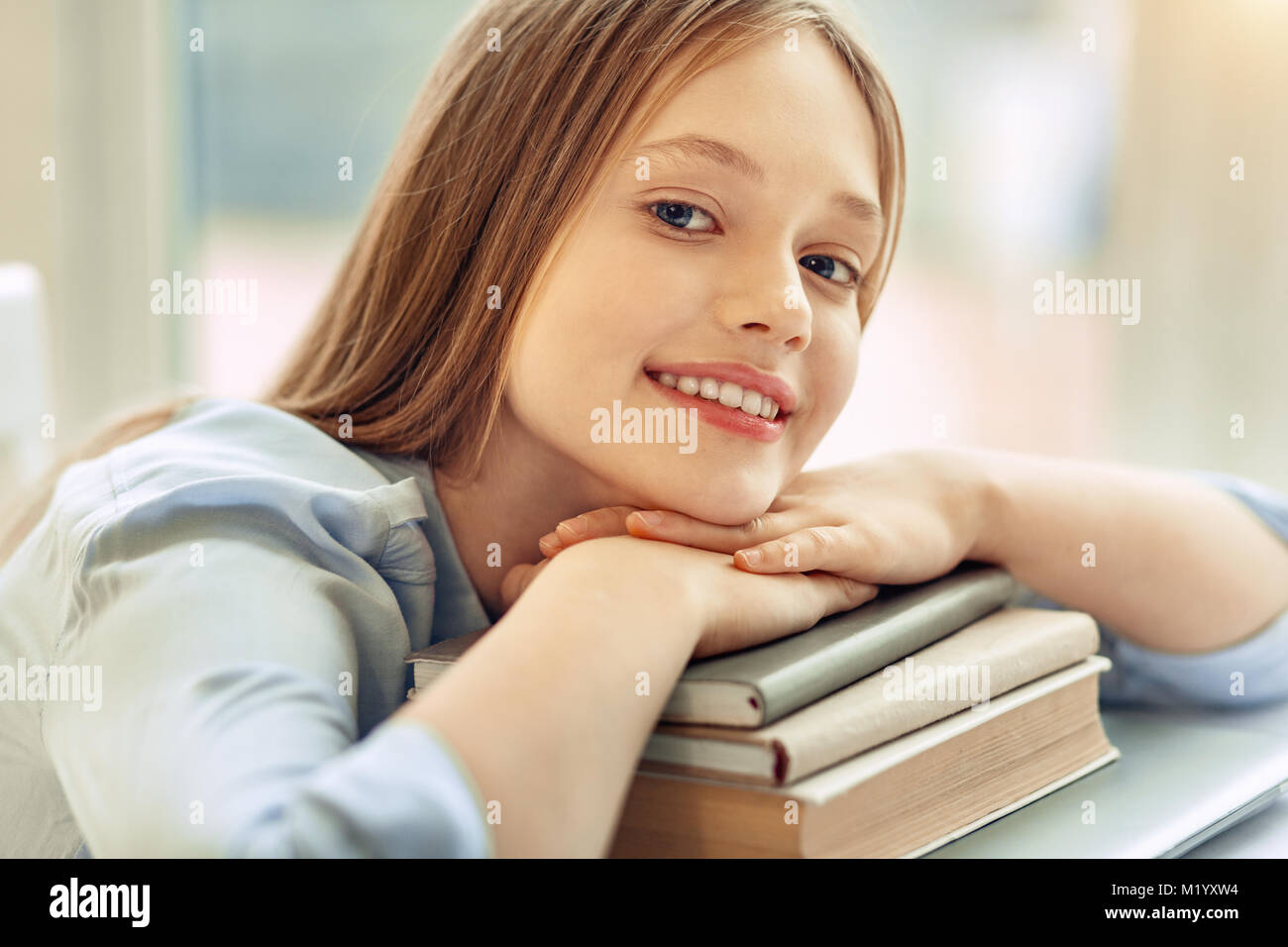Pretty girl resting her chin on pile of books Stock Photo - Alamy