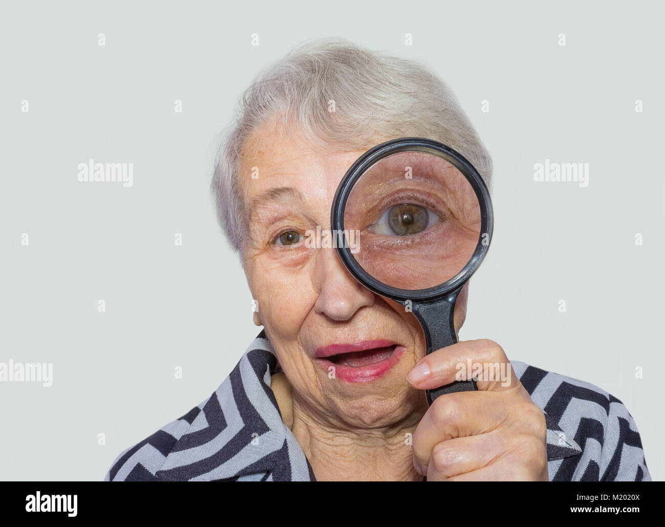 portrait of senior woman looking through a magnifying glass over white background Stock Photo