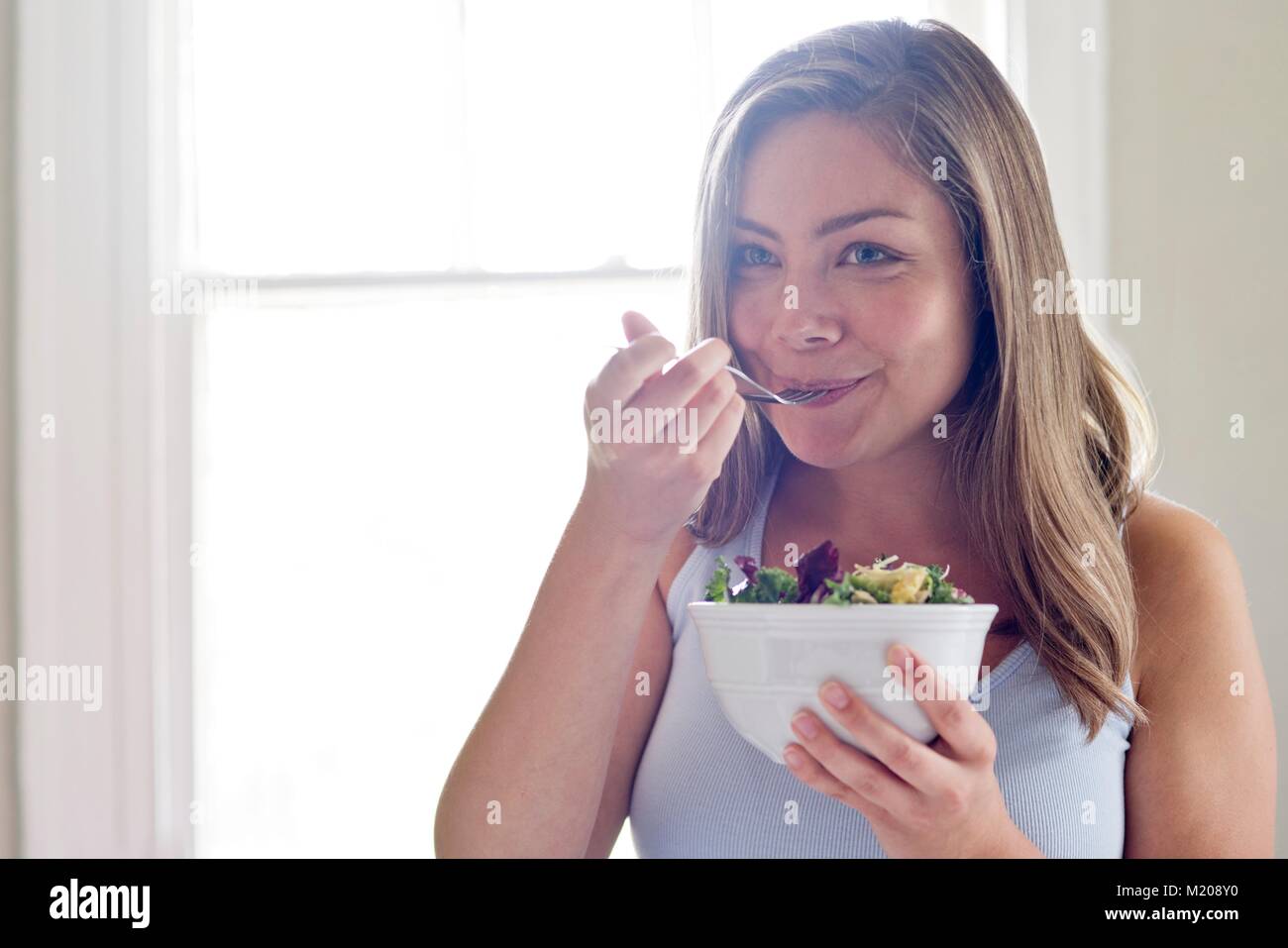 Portrait of young woman eating salad. Stock Photo