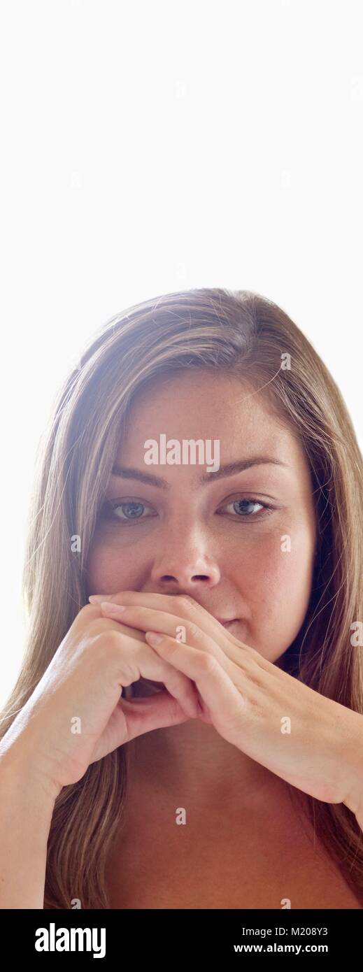 Portrait of young woman with hands covering mouth. Stock Photo