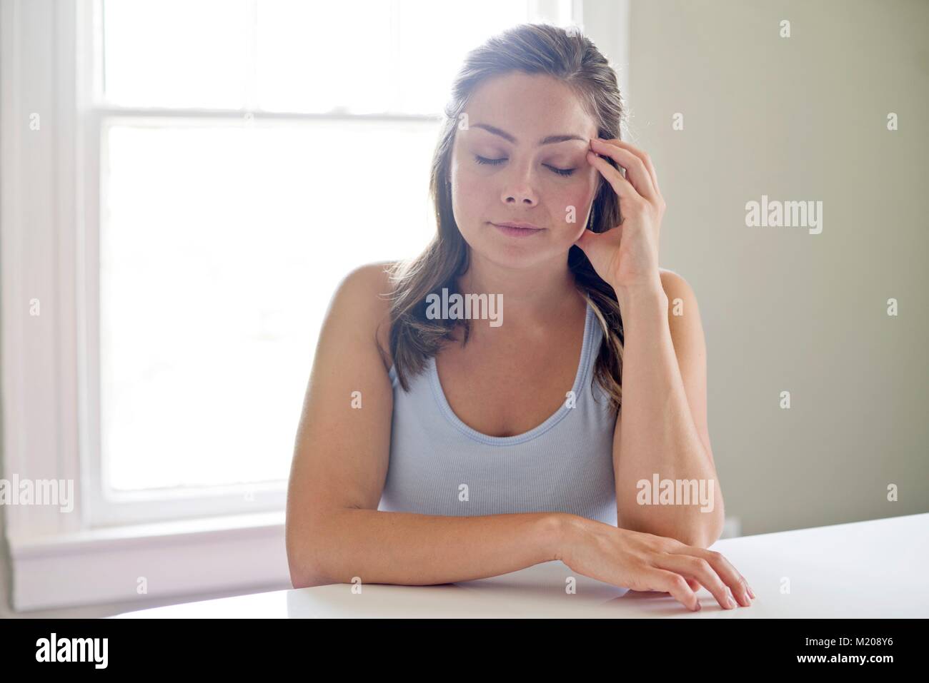 Portrait of young woman touching head with eyes closed. Stock Photo