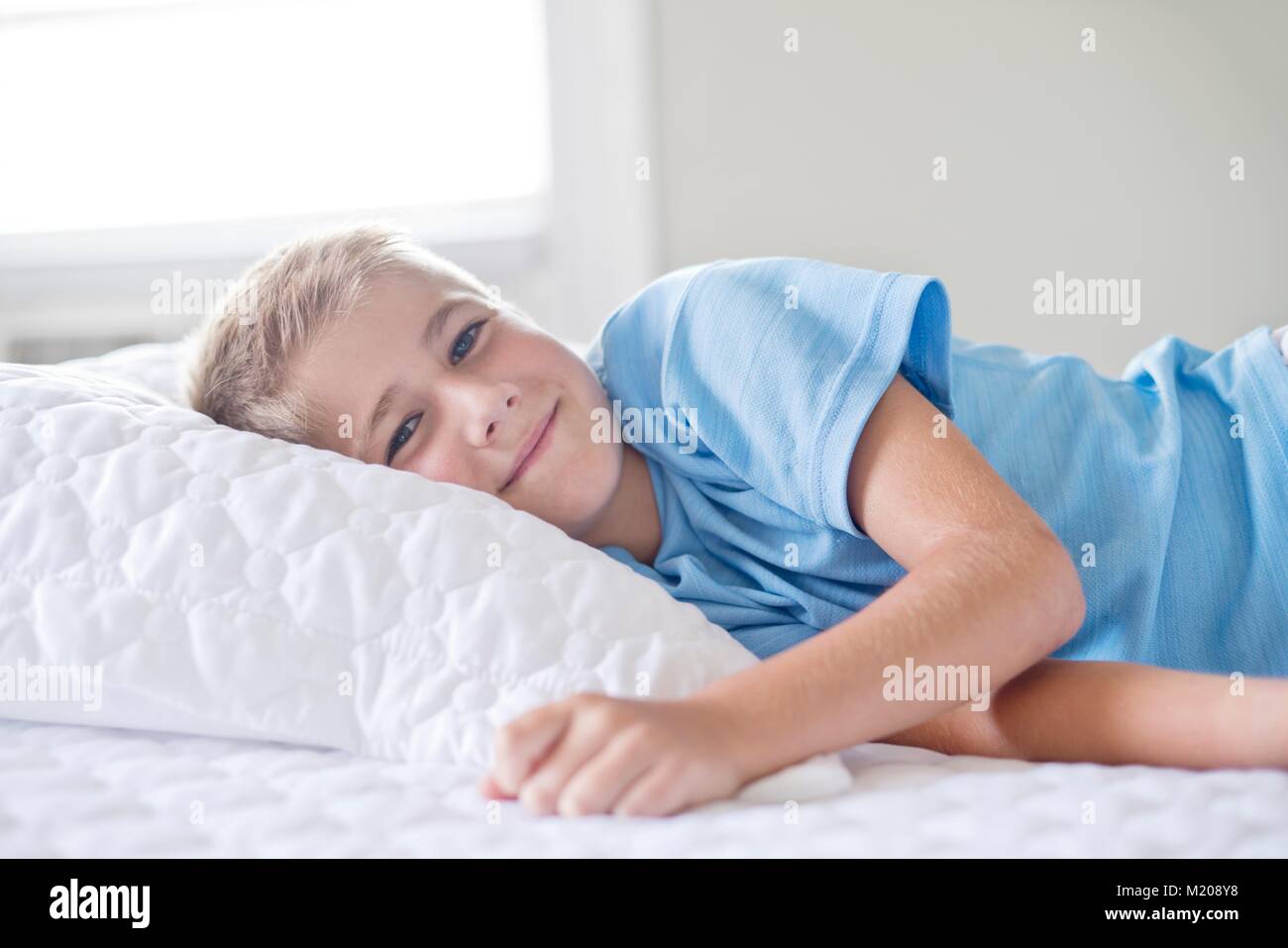 Young boy lying with head on pillow, smiling. Stock Photo