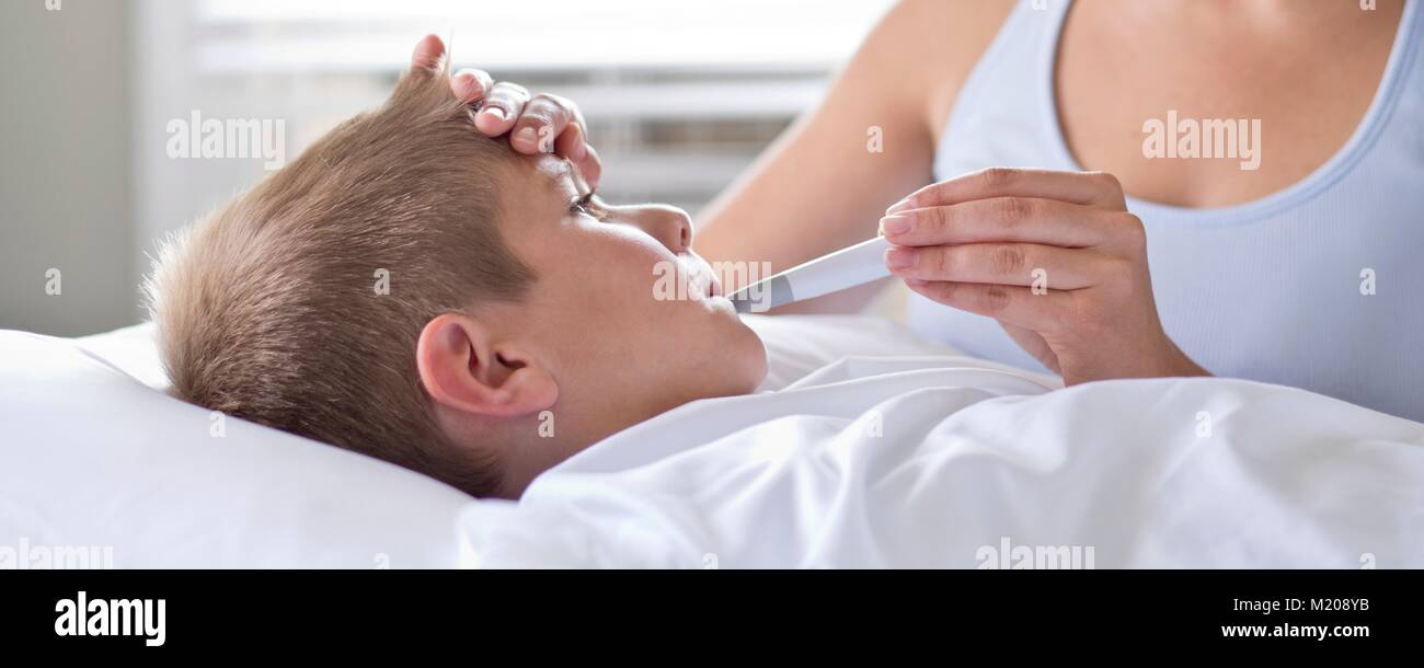 Mother taking son's temperature in bed. Stock Photo