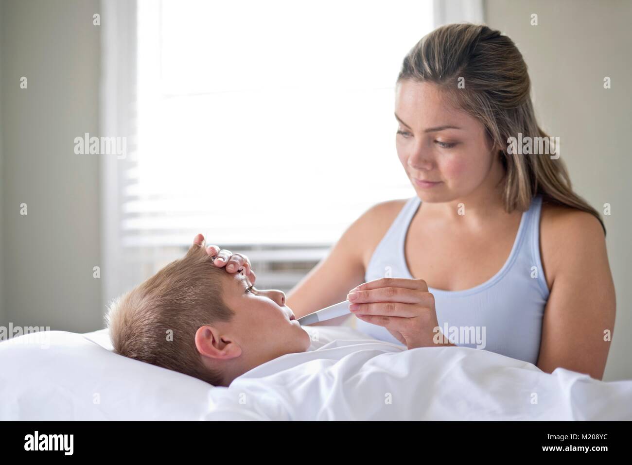 Mother taking son's temperature in bed. Stock Photo