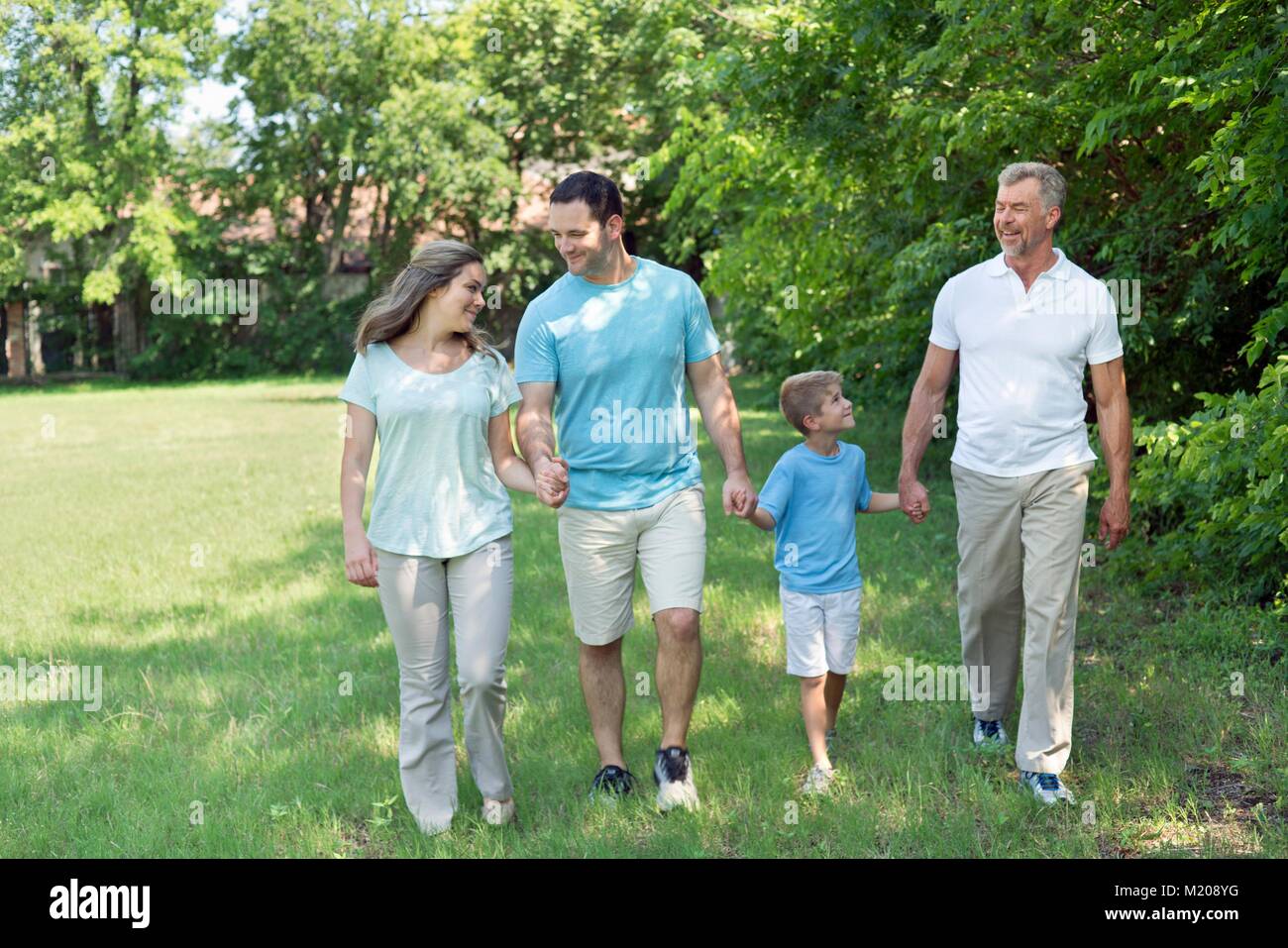 Family walking in park holding hands. Stock Photo
