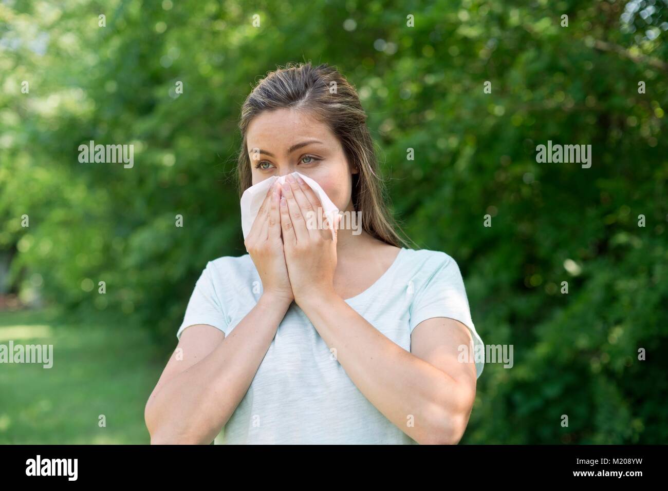Young woman blowing her nose on a tissue. Stock Photo