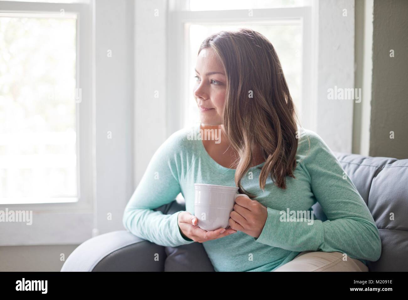 Young woman holding a mug and looking away. Stock Photo