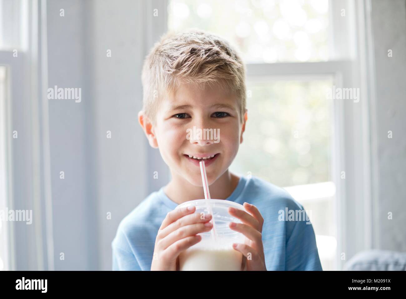 Portrait of a young boy drinking milk through a straw. Stock Photo