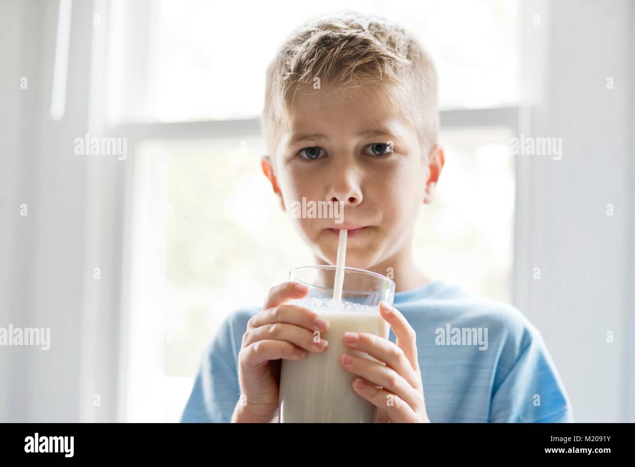 Portrait of a young boy drinking milk through a straw. Stock Photo