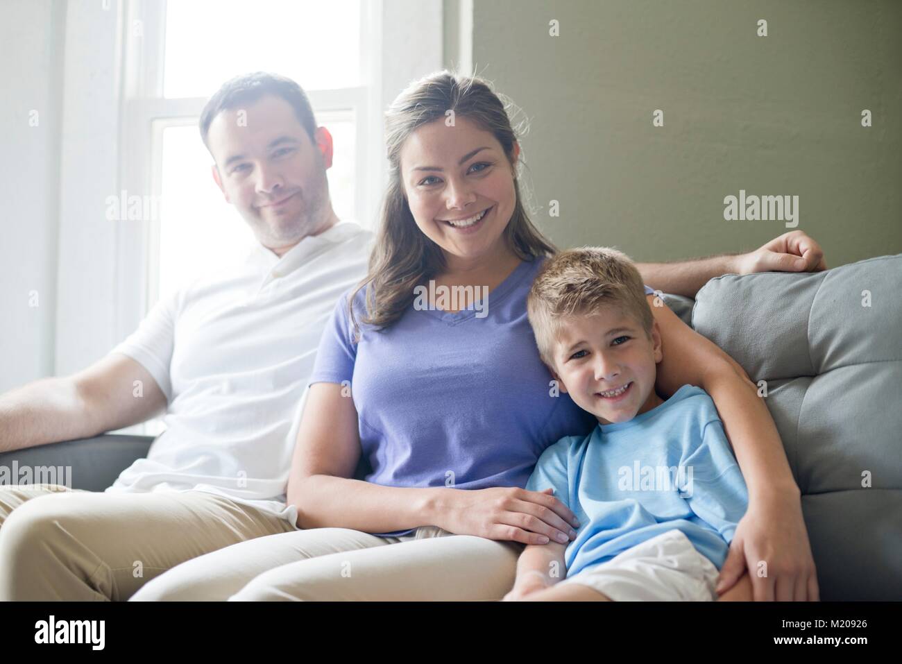Boy sitting on sofa with his mother and father, portrait. Stock Photo