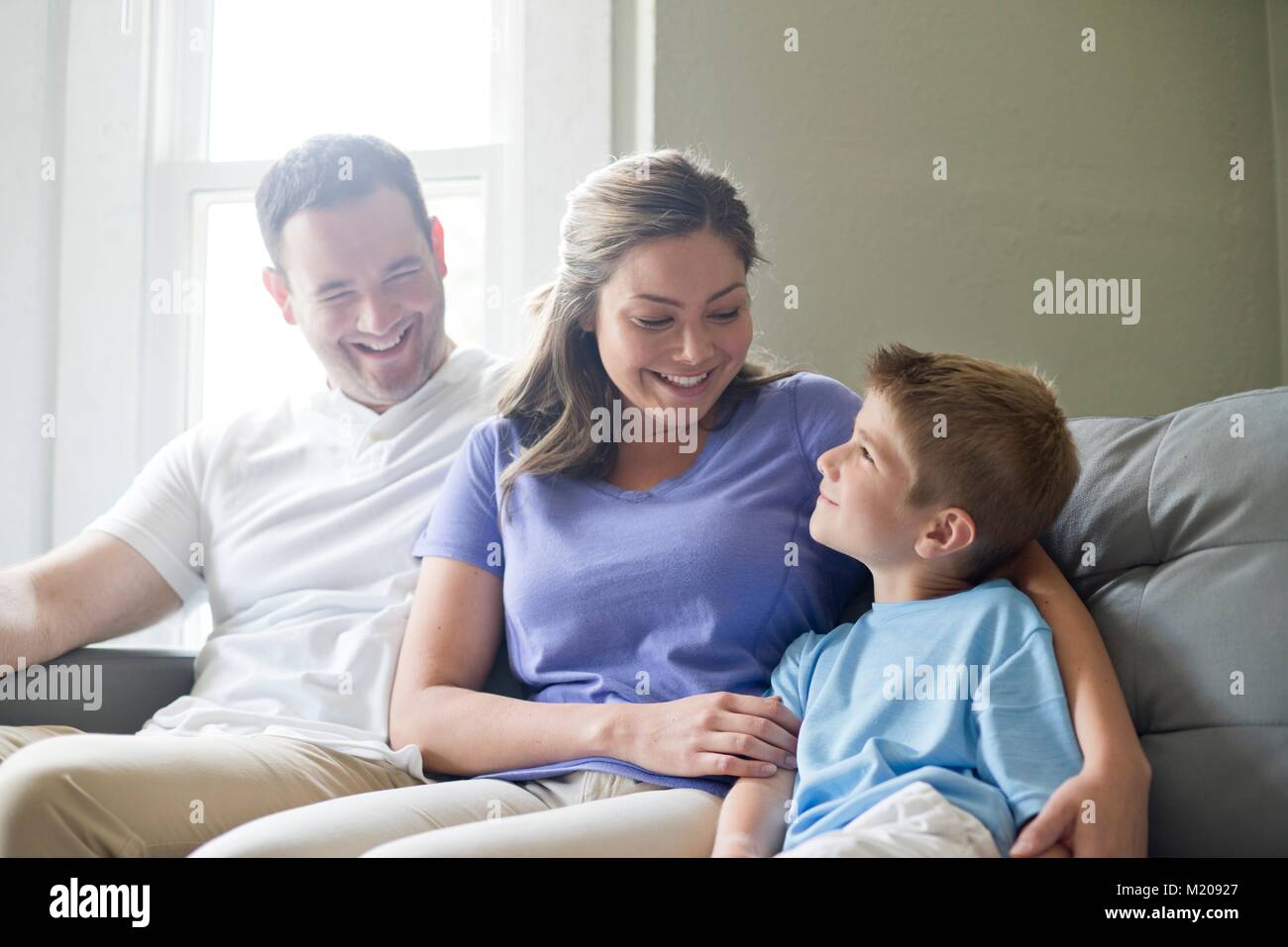 Boy sitting on sofa with his mother and father, portrait. Stock Photo