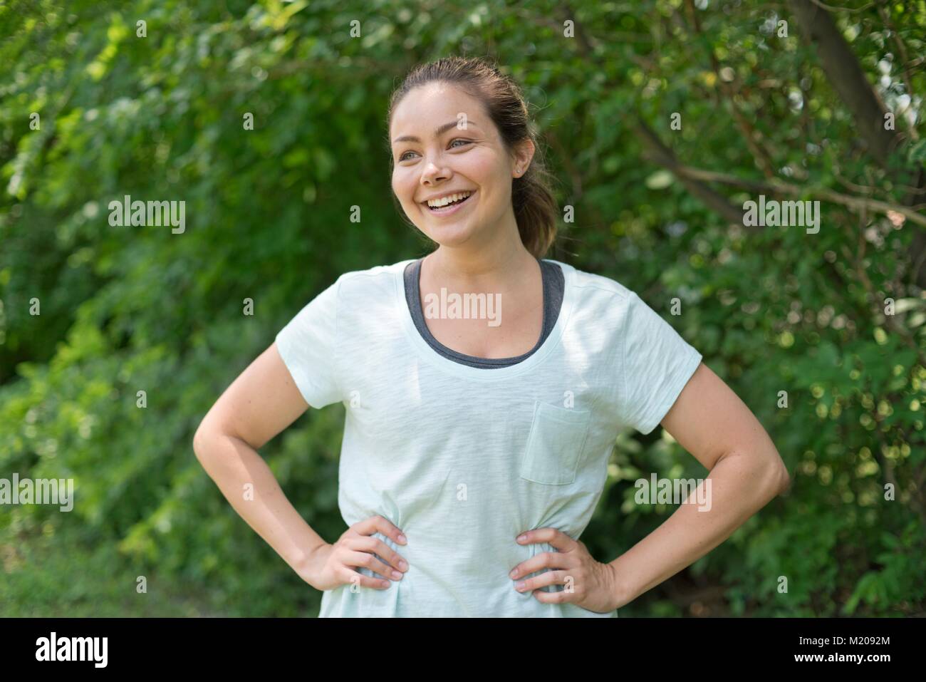 Young woman with hands on hips, smiling. Stock Photo