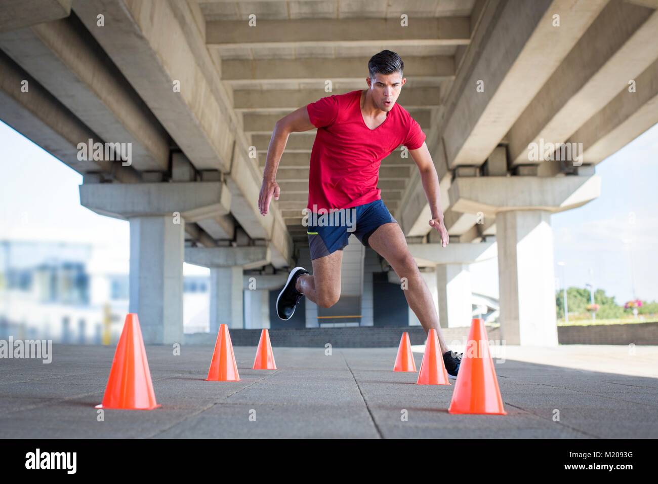 Young men running around plastic cones. Stock Photo