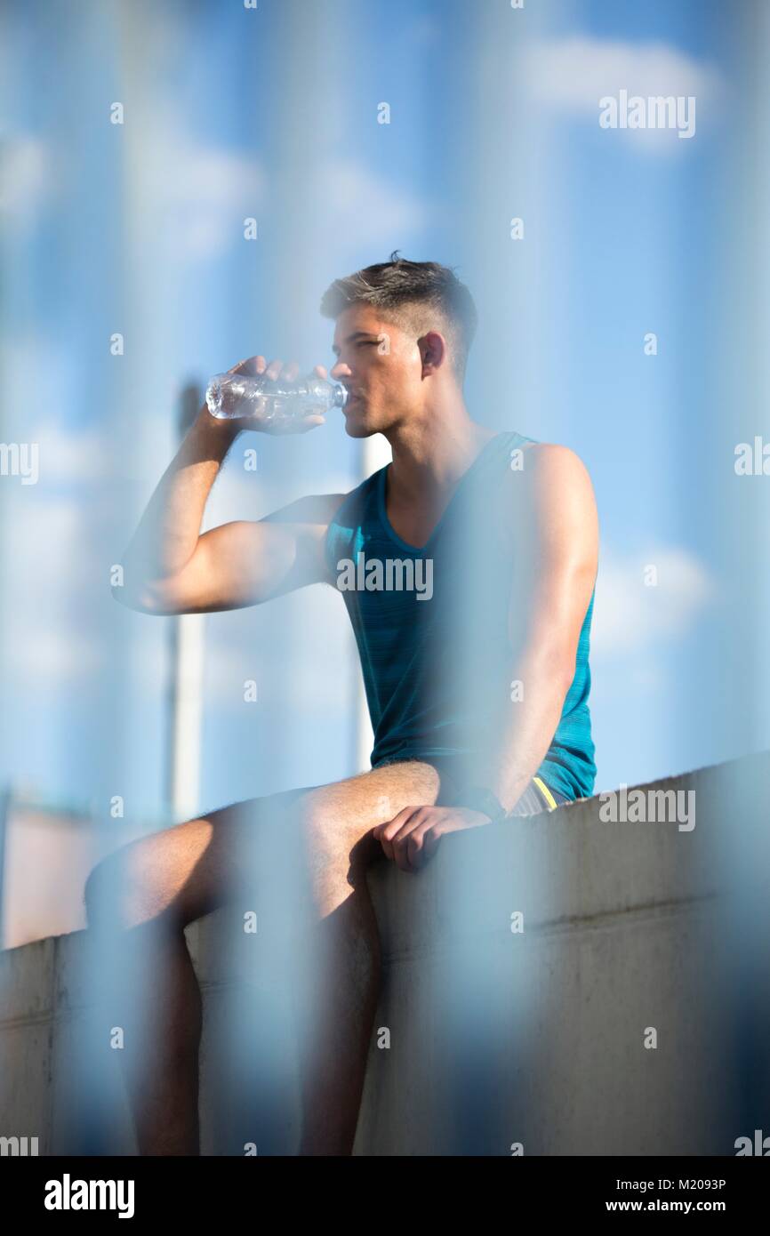 Young man drinking bottle of mineral water. Stock Photo