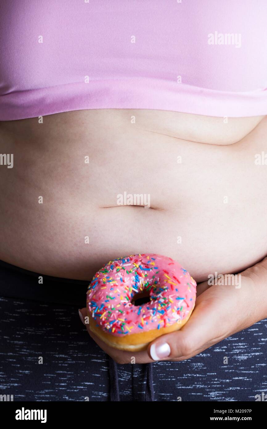 MODEL RELEASED. Woman holding doughnut in front of belly. Stock Photo