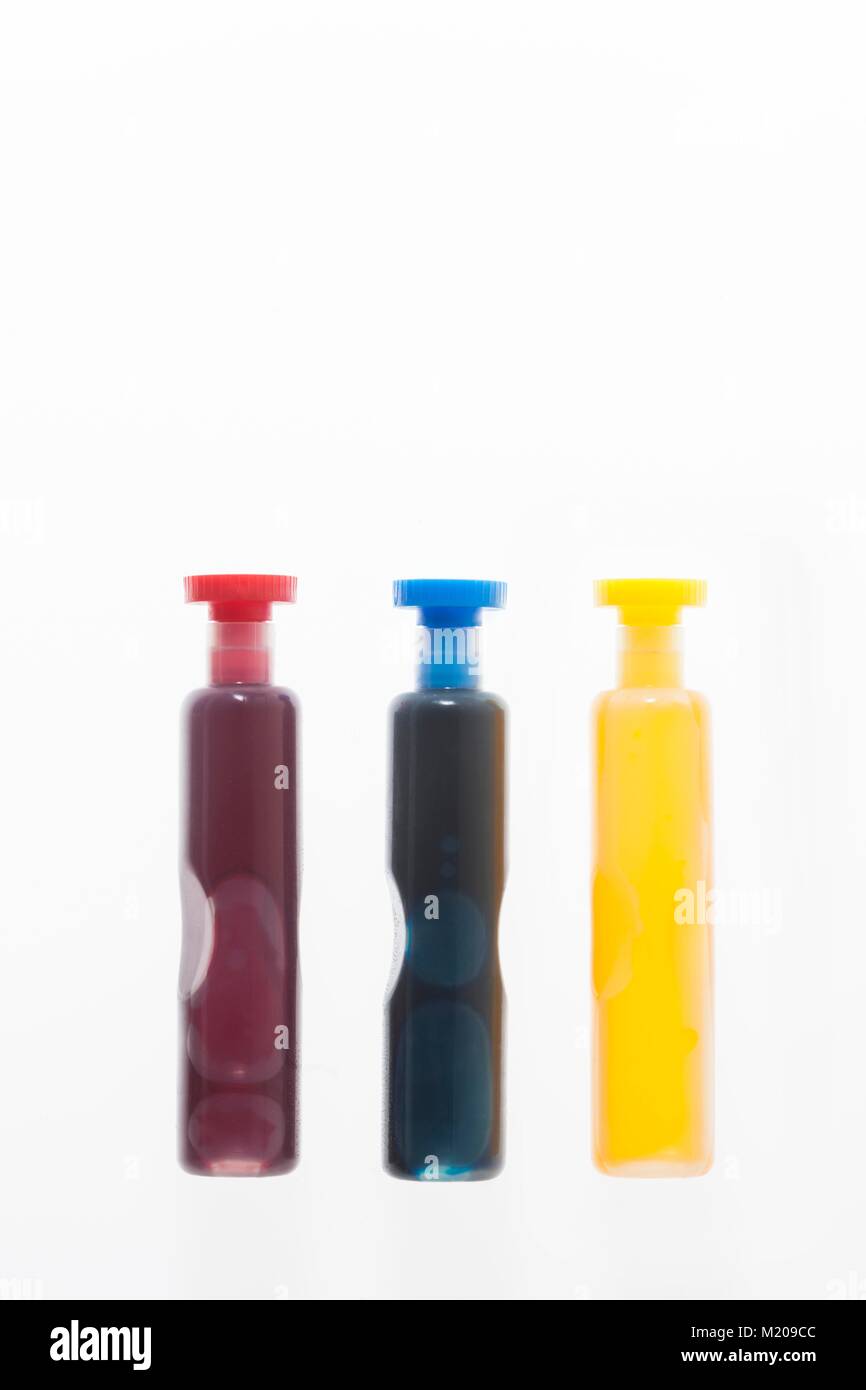 Three containers with red, blue and yellow liquid, studio shot. Stock Photo