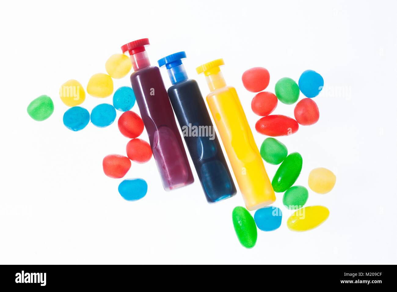 Three containers with red, blue and yellow liquid spots, studio shot. Stock Photo