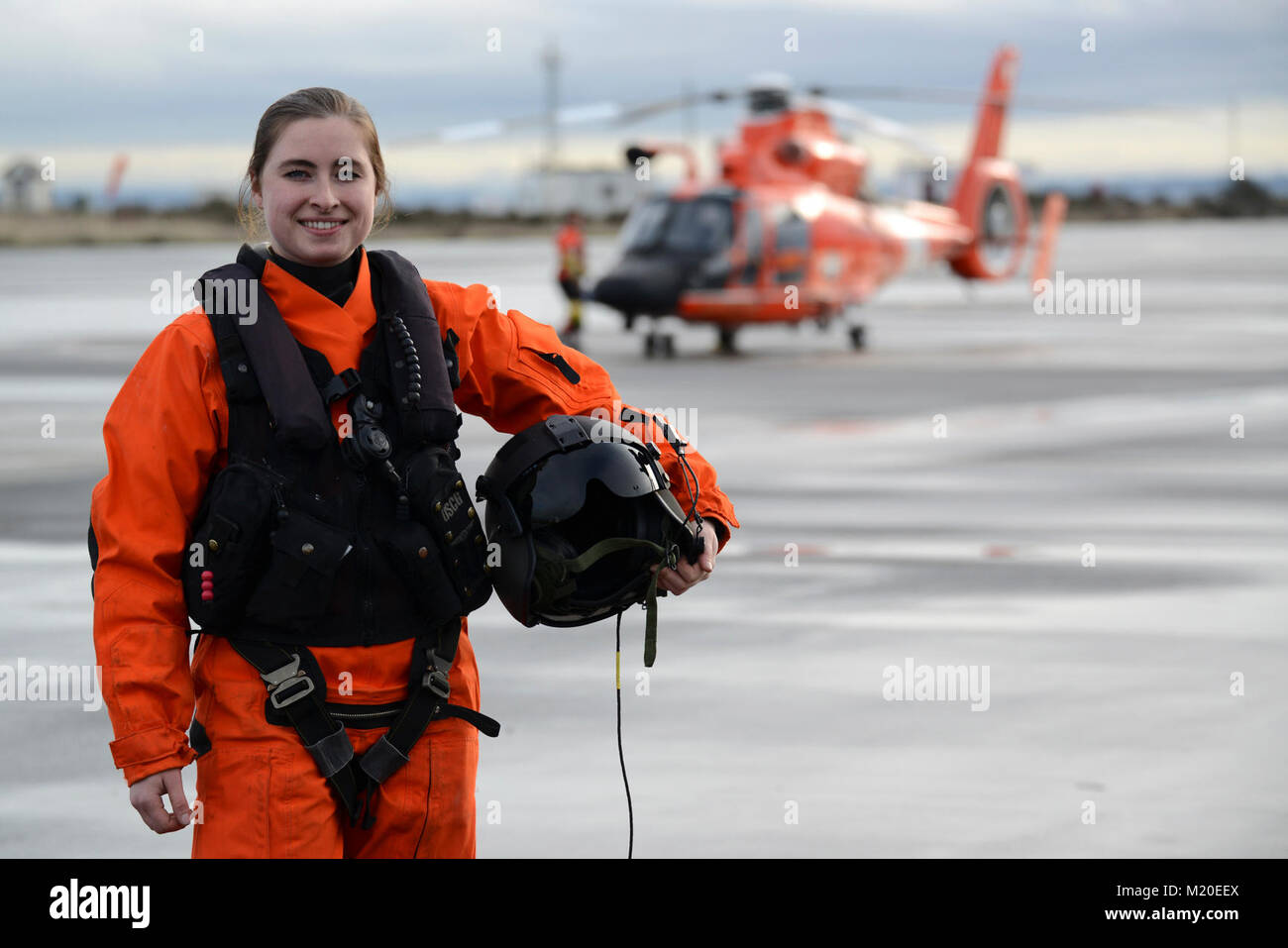 Coast Guard Petty Officer 3rd Class Amber Brewer, an aviation maintenance technician, Air Station Port Angeles, Wash., poses for a picture on the the flight line in front of an MH-65 Dolphin Helicopter, Jan. 26, 2018.    Brewer not only maintains the readiness of the aircraft, but is also a qualified flight mechanic responsible for overseeing the mechanical safety of the helicopter and conducting the essential hoisting operations conducted during rescue swimmer deployments.    U.S. Coast Guard Stock Photo