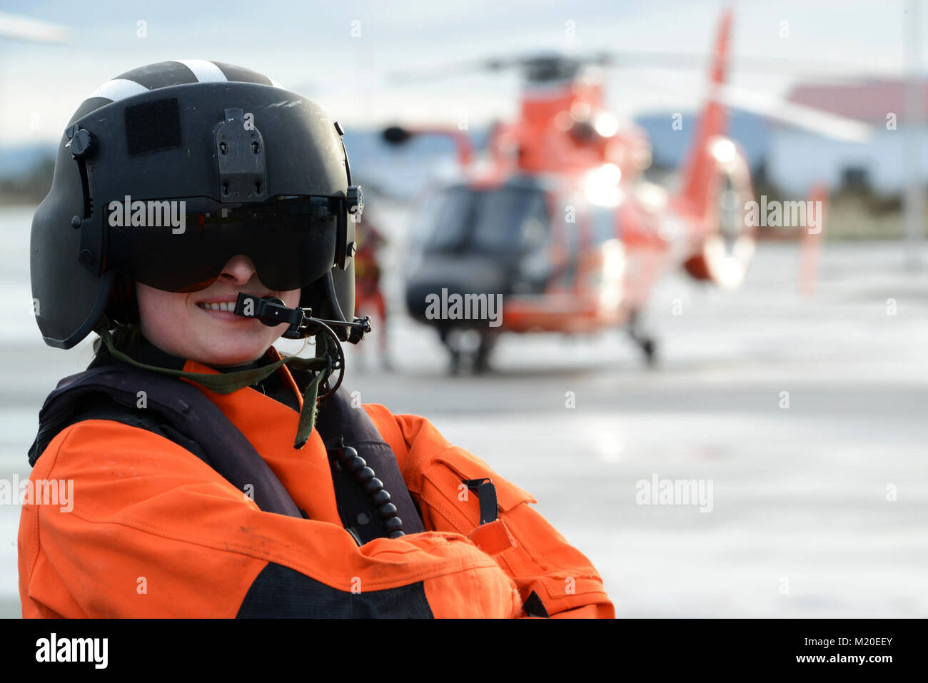 Coast Guard Petty Officer 3rd Class Amber Brewer, an aviation maintenance technician, Air Station Port Angeles, Wash., poses for a picture on the the flight line in front of an MH-65 Dolphin Helicopter, Jan. 26, 2018.    Brewer not only maintains the readiness of the aircraft, but is also a qualified flight mechanic responsible for overseeing the mechanical safety of the helicopter and conducting the essential hoisting operations conducted during rescue swimmer deployments.    U.S. Coast Guard Stock Photo