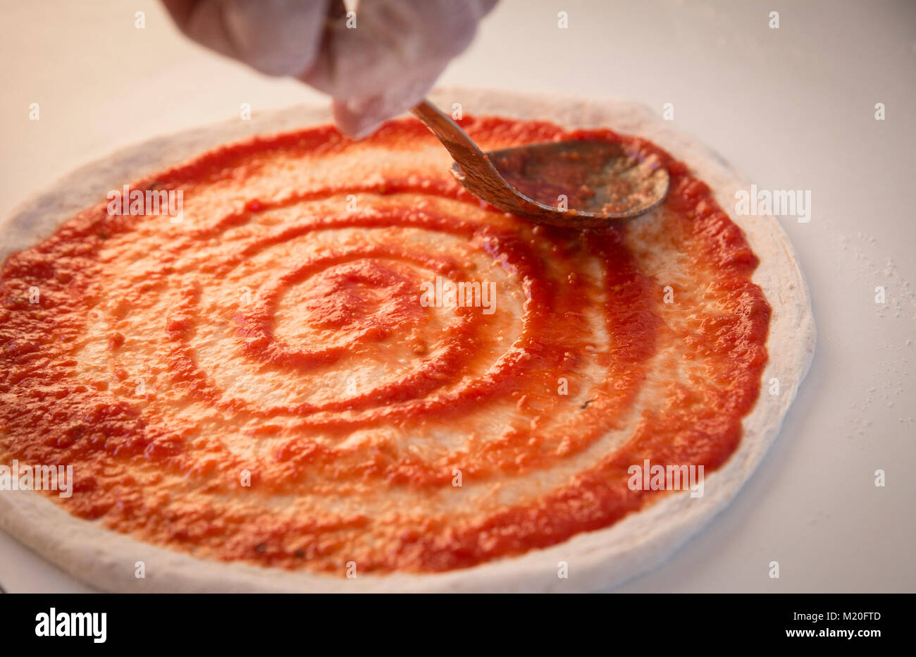 Placing tomato sauce on pizza dough Stock Photo - Alamy