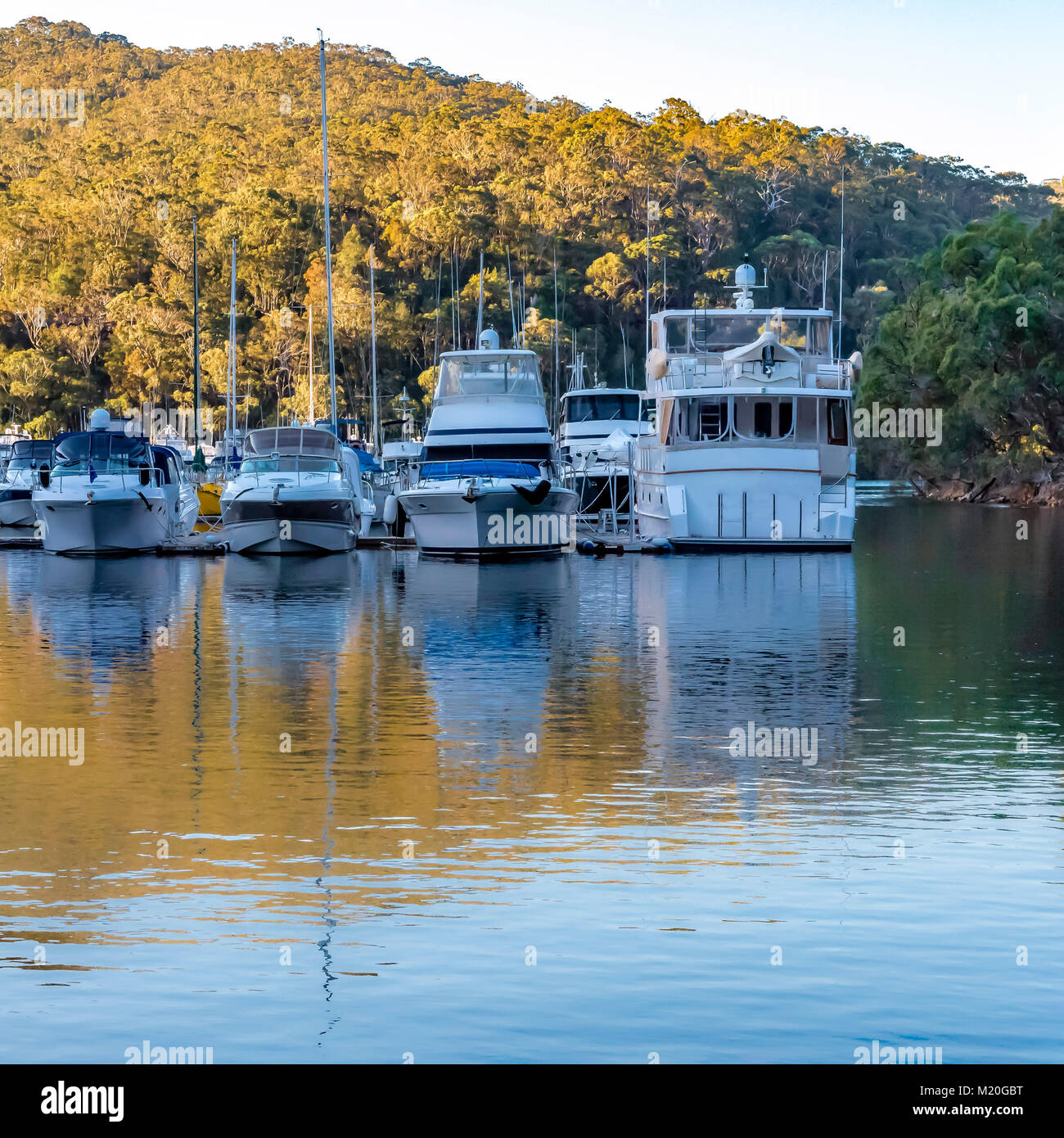 Sailing yachts in marine port, autumn colors, Akuna Bay, Sydney, Australia. Golden reflection on the water and sail boats at the Marina in Broken Bay. Stock Photo
