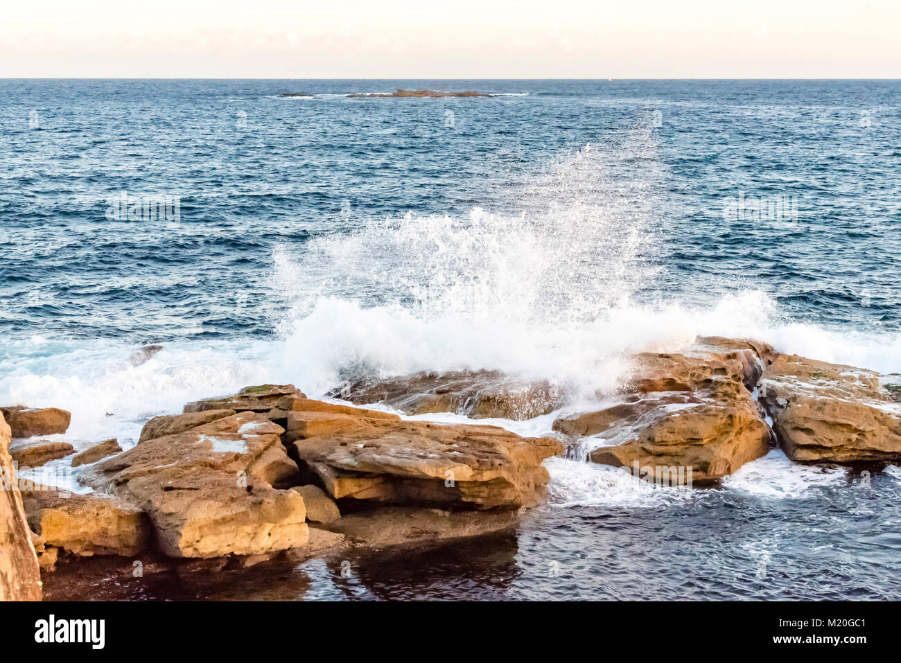 Scenic view of blue Pacific ocean and Australian coast with waves crashing on rocks, daytime.  Sea water splashing, Coogee Beach, Sydney, Australia. Stock Photo