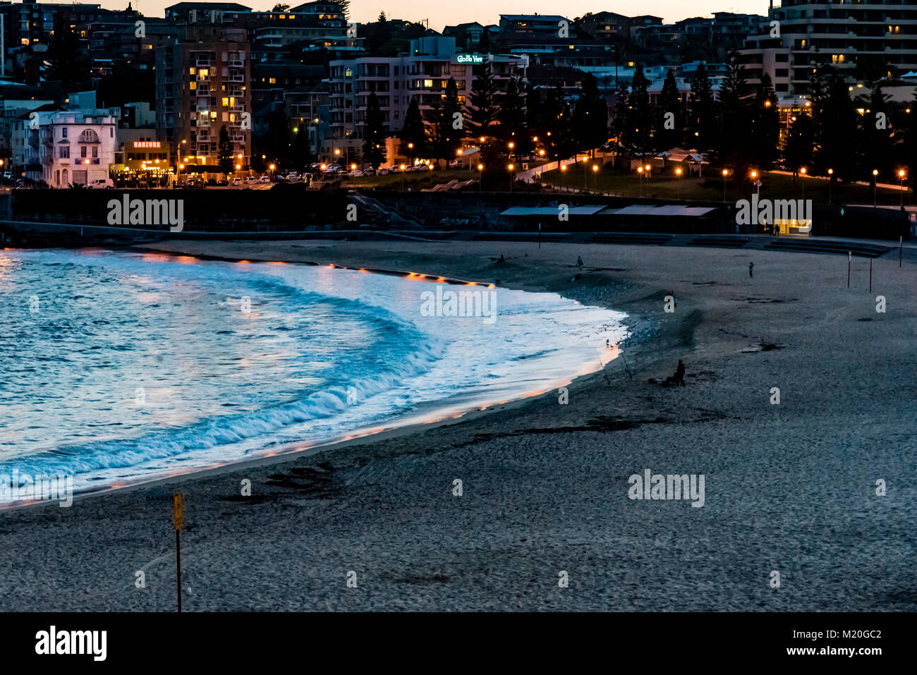 Panorama of beach ocean and city lights, Coogee Beach, Sydney, Australia. Evening cityscape of calm beach lights of buildings reflecting on ocean. Stock Photo