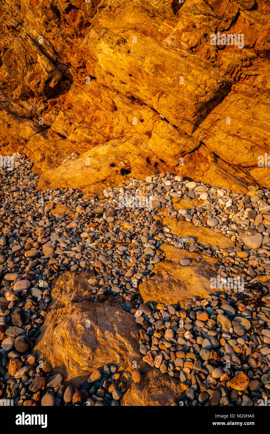 Golden cliffs, pebbles and rocks at Church Bay, Anglesey, Wales in summer sunshine Stock Photo